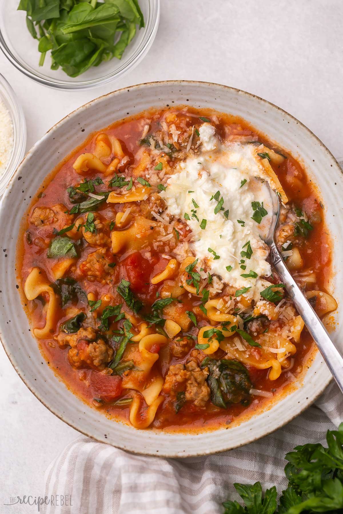 Cette recette de soupe aux lasagnes à la mijoteuse est pleine de saveurs ! Il a une base de tomate, faite de saucisses italiennes, de nouilles à lasagne et de nombreuses herbes et fromages italiens. Il peut également être préparé dans l'Instant Pot !#crockpot #slowcooker #soupe #dinner #recipes Vue aérienne d'un bol plein de soupe de lasagne avec une cuillère dedans.