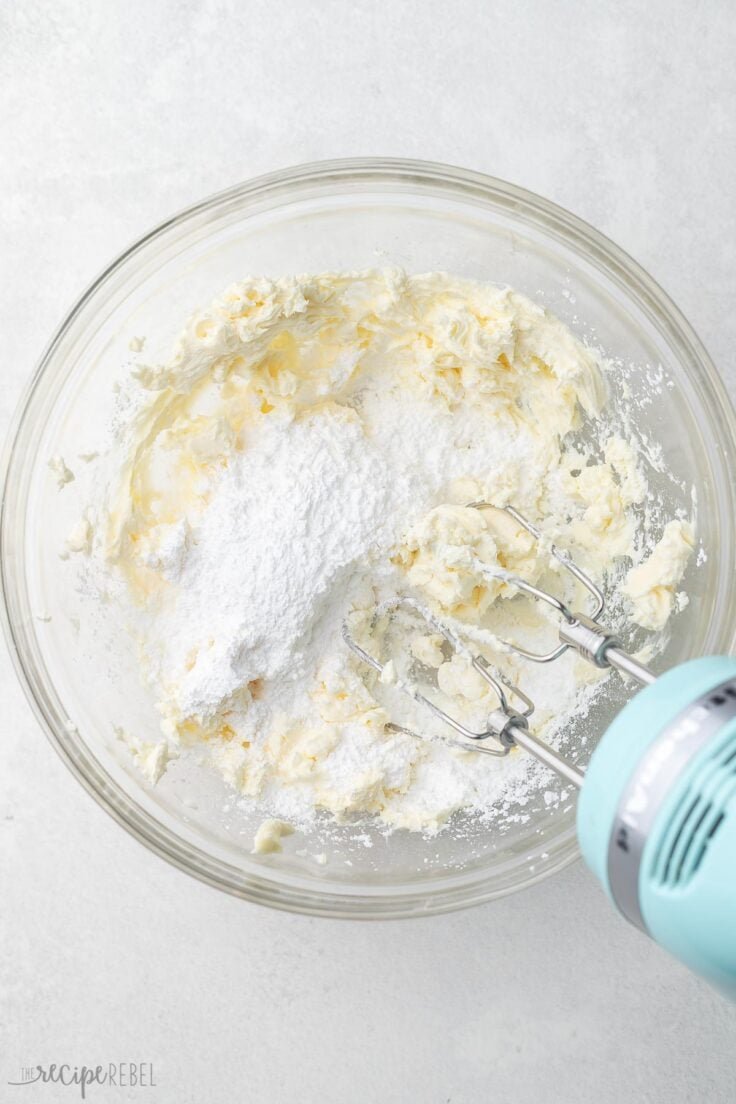 sucre en poudre ajouté au bol de mélange avec un mélangeur à côté.
