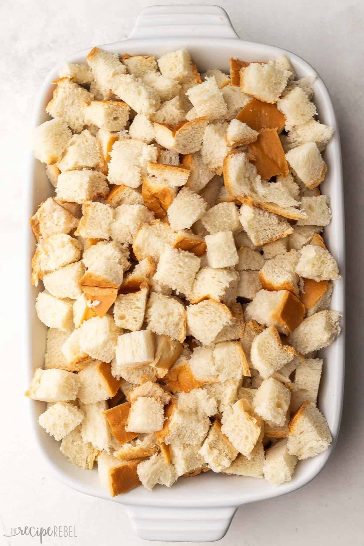 plat de cuisson blanc rempli de pain français coupé en cubes.