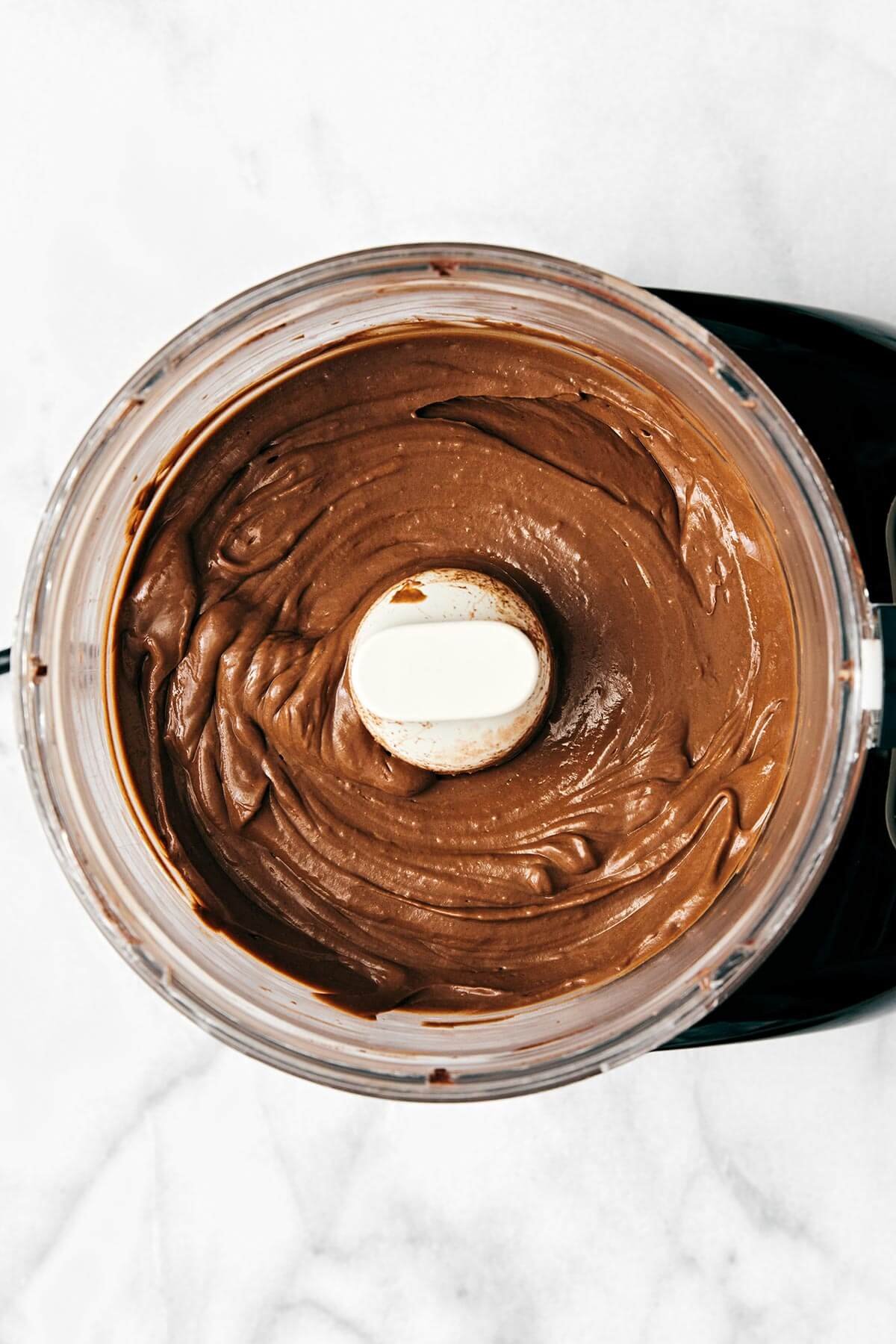 Cette recette facile de pudding au chocolat à l'avocat est l'un de mes desserts sains préférés de tous les temps ! De plus, elle est végétalienne et sans produits laitiers. Mélange du pudding au chocolat à l'avocat dans un robot culinaire.