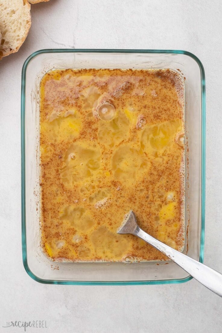 un plat en verre et une fourchette avec les ingrédients du pain perdu mélangés.
