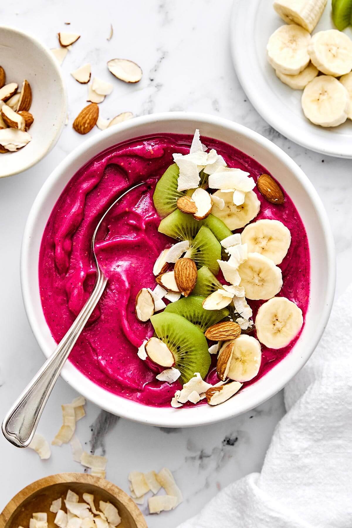 Rafraîchissant et riche en nutriments, ce bol de smoothie pitaya est le petit déjeuner léger ou l'en-cas sain parfait ! Bol de smoothie pitaya avec des fruits sur le dessus.