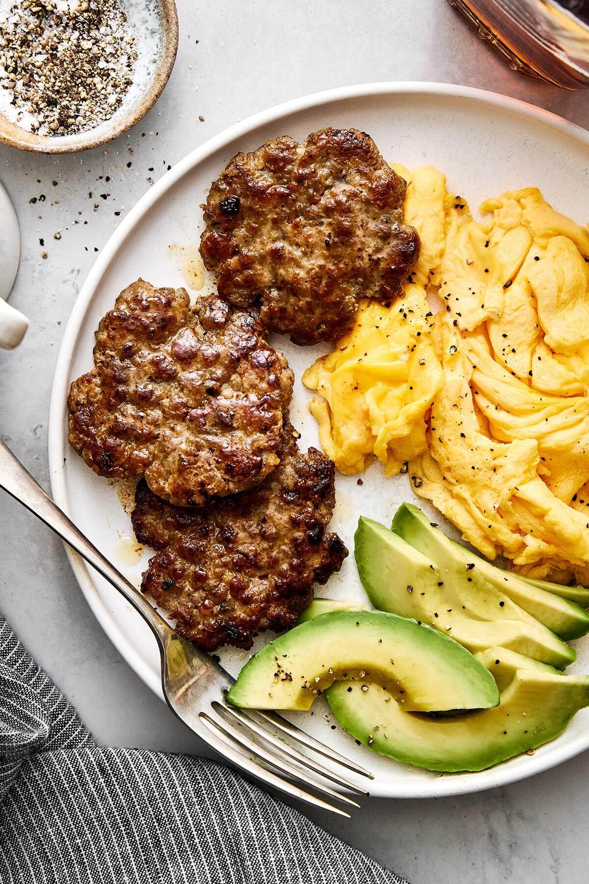 Savoureuse et juteuse, cette saucisse de petit-déjeuner maison apporte un boost de protéines pleine de saveur. Assiette de saucisses de petit-déjeuner et œufs.