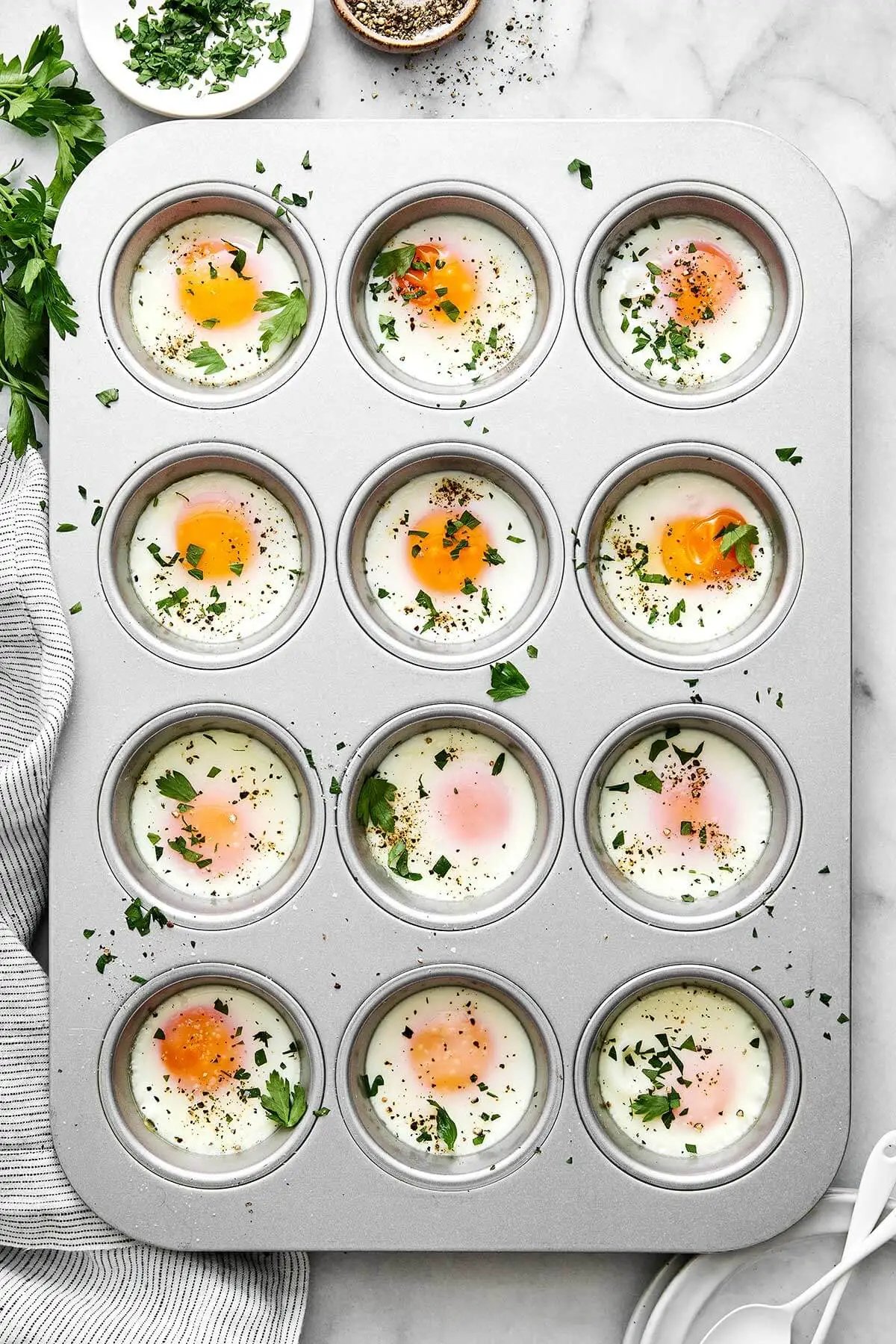 Ces œufs au four sont la plus simple façon de servir des œufs au petit-déjeuner ou au brunch ! Ils cuisent rapidement et sont parfaitement portionnés ! Œufs au four dans un moule à muffins.
