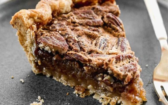 tranche de tarte aux noix de pécan sur une assiette grise.