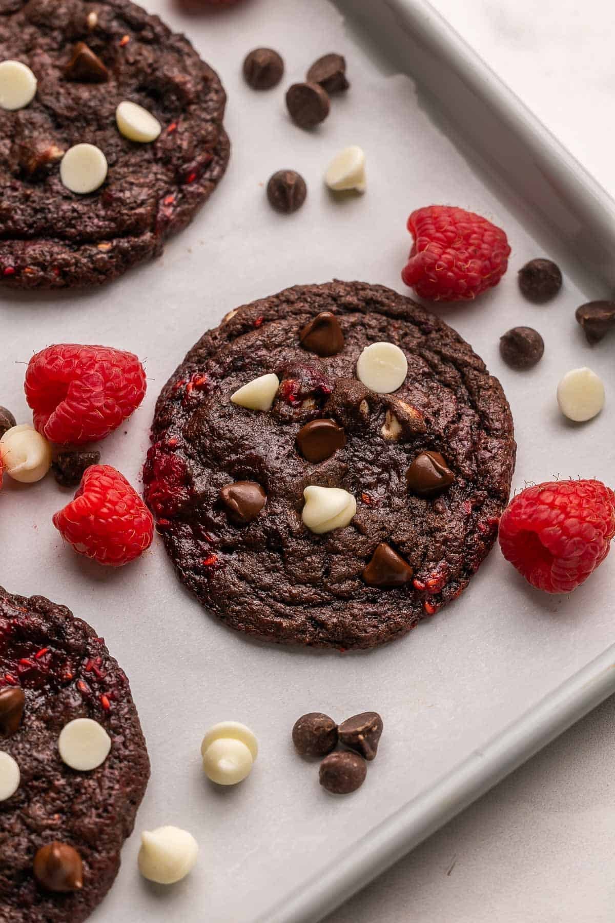 cookies triple chocolat framboise dans un plat avec des pépites de chocolat à côté.