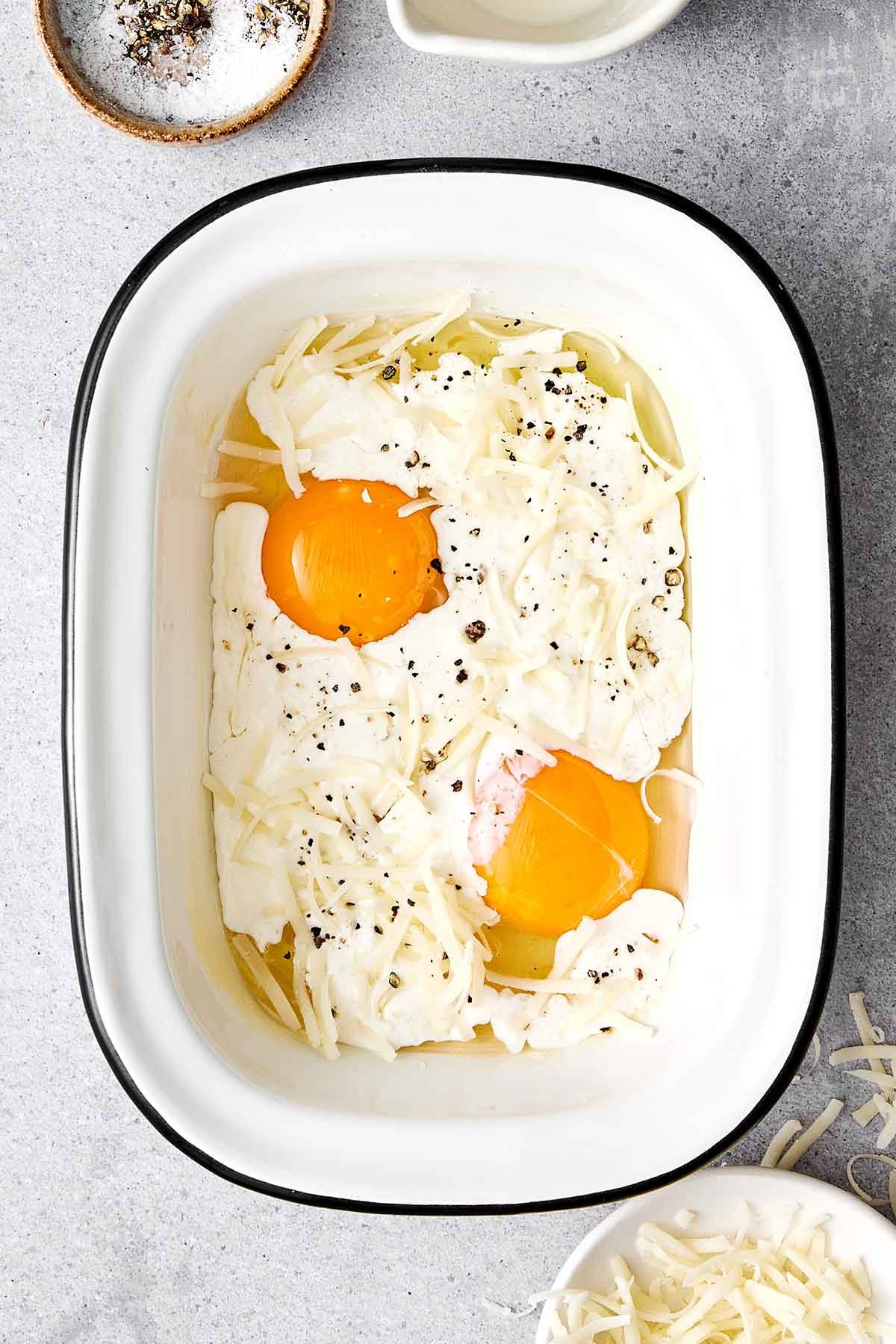 Ces oeufs en cocotte sont la manière la plus facile d'élever votre petit-déjeuner et votre brunch ! Ils sont légèrement crémeux, un peu fromagés, et tellement délicieux. Étape deux des oeufs en cocotte : Ajouter la crème et le fromage.