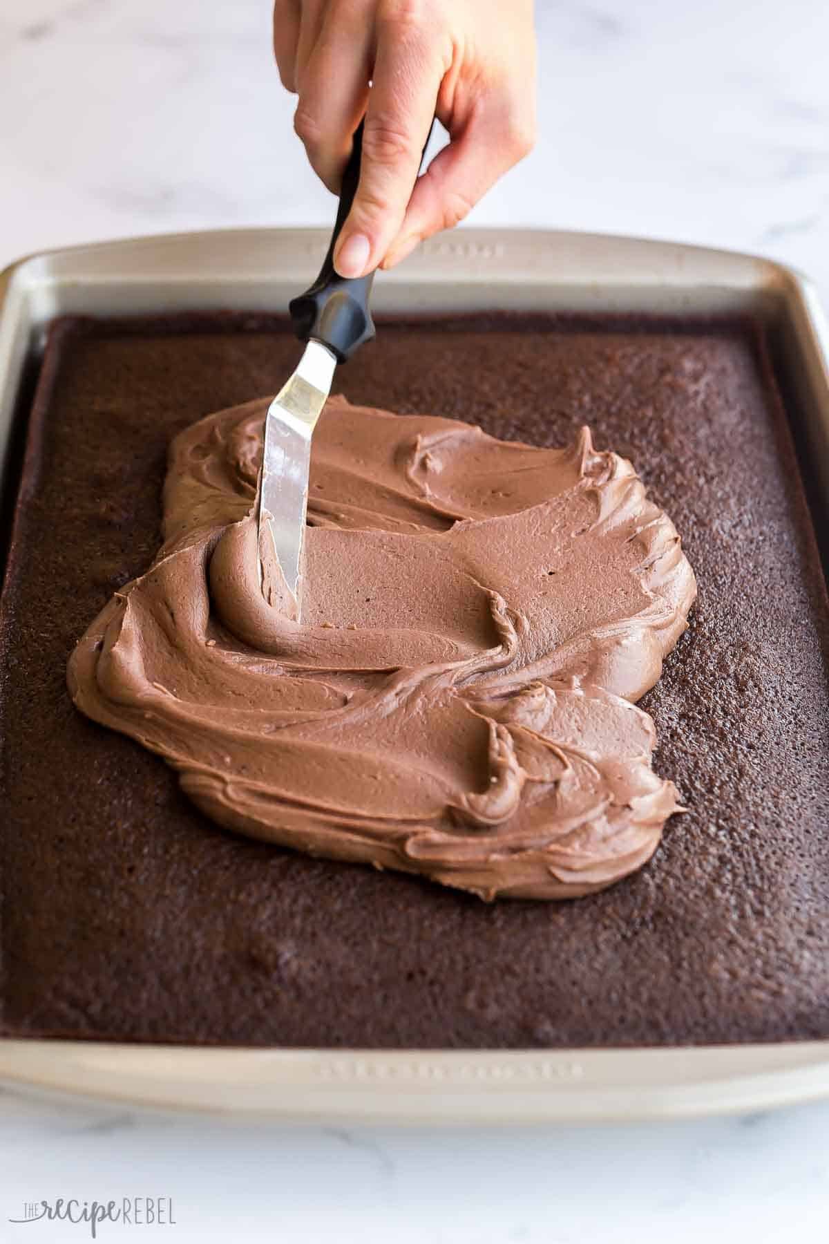étalement du glaçage sur un gâteau au chocolat avec une spatule offset.