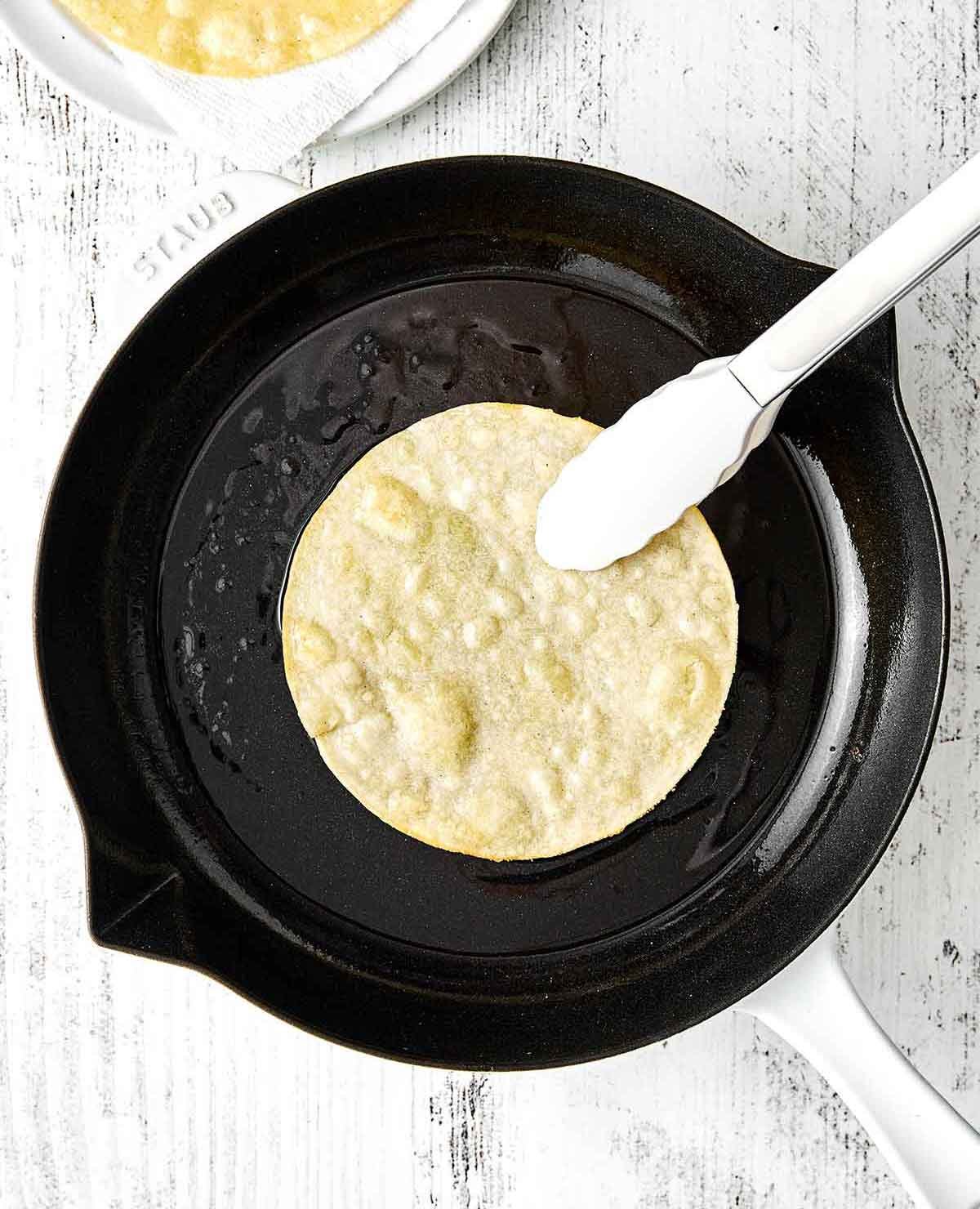 Faire frémir une tortilla dans une poêle pour les huevos rancheros.
