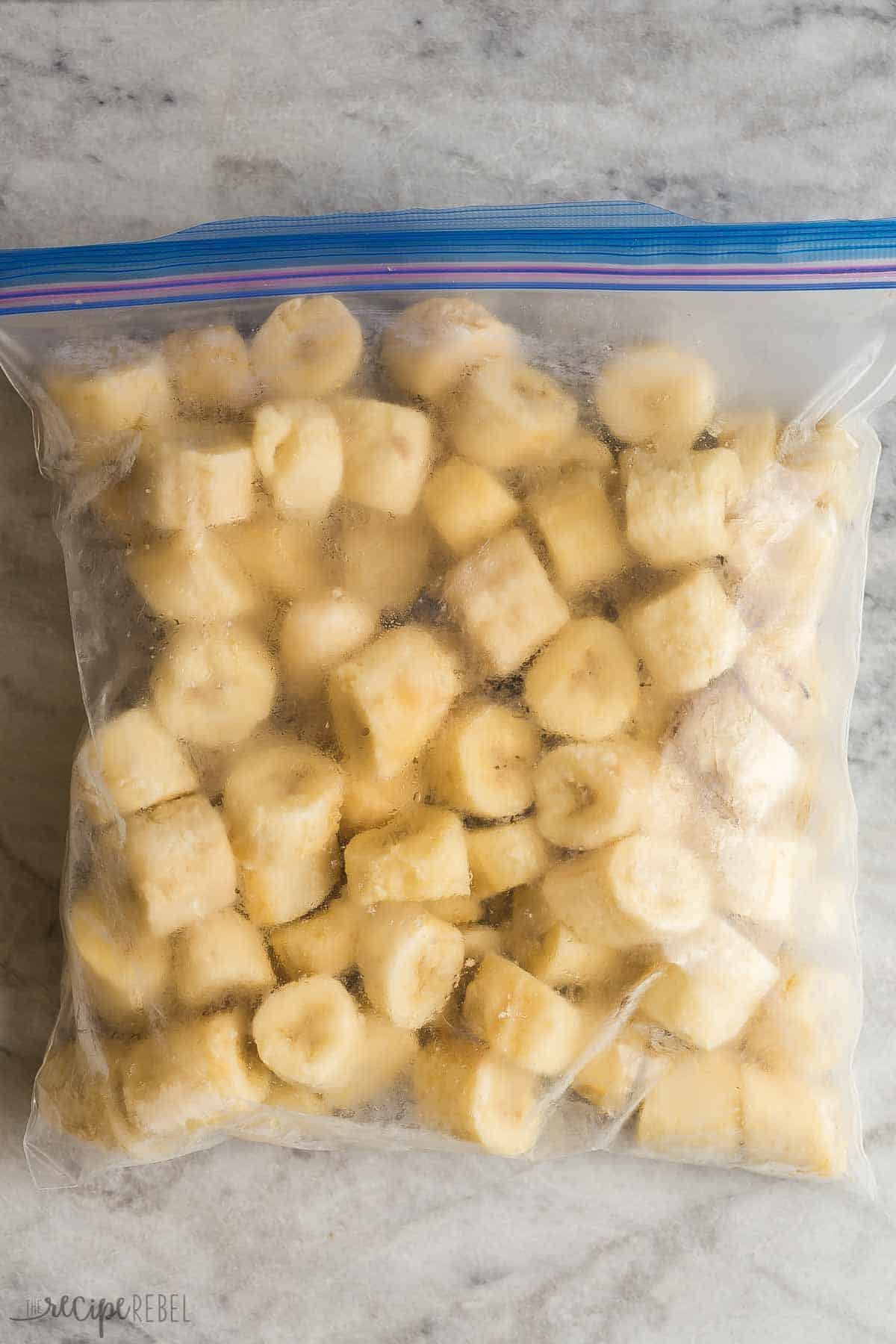 bananes tranchées congelées dans un sachet de congélation sur un fond en marbre.