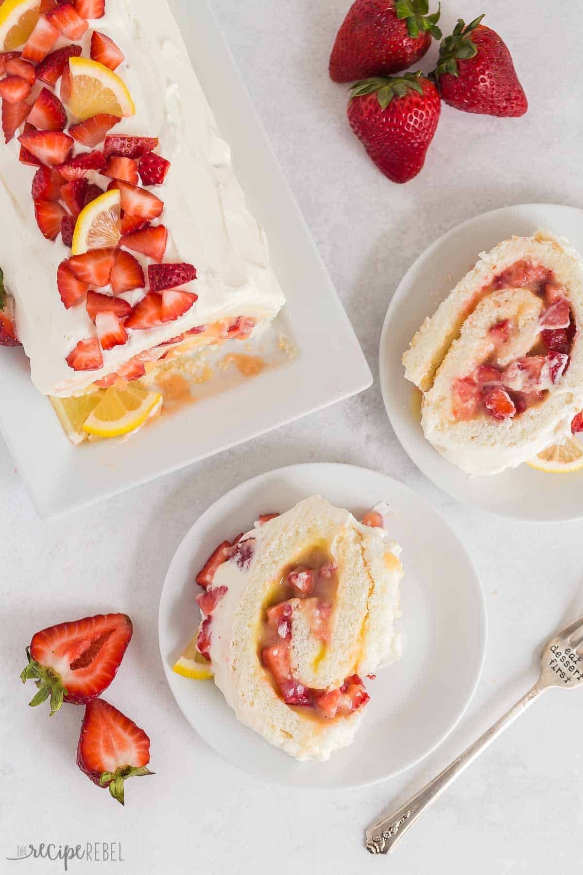 image vue de dessus d'un rouleau de gâteau angelique à la fraise et au citron avec deux tranches coupées et sur des assiettes blanches.