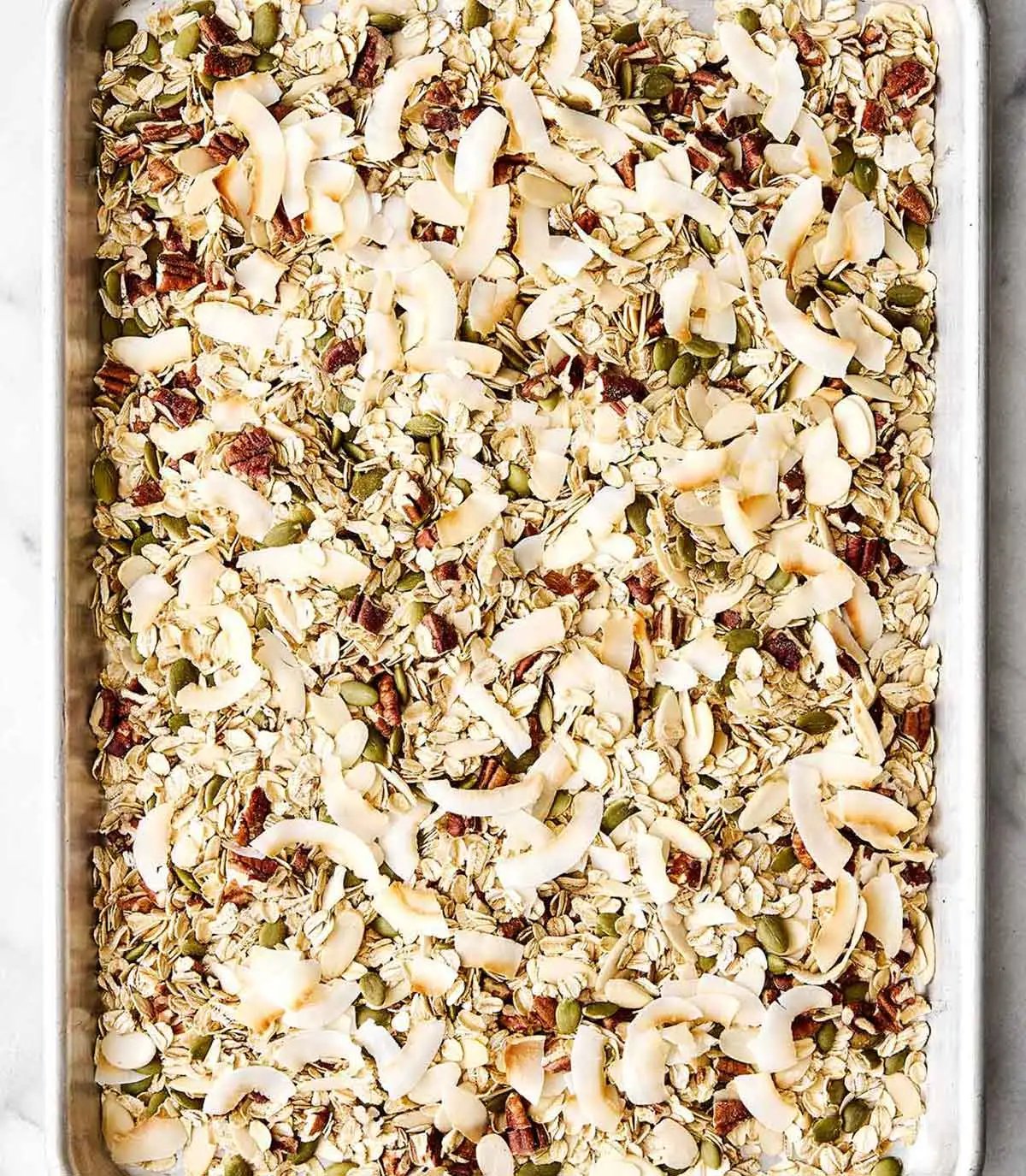Torréfaction des flocons de noix de coco avec les ingrédients du muesli sur une plaque.