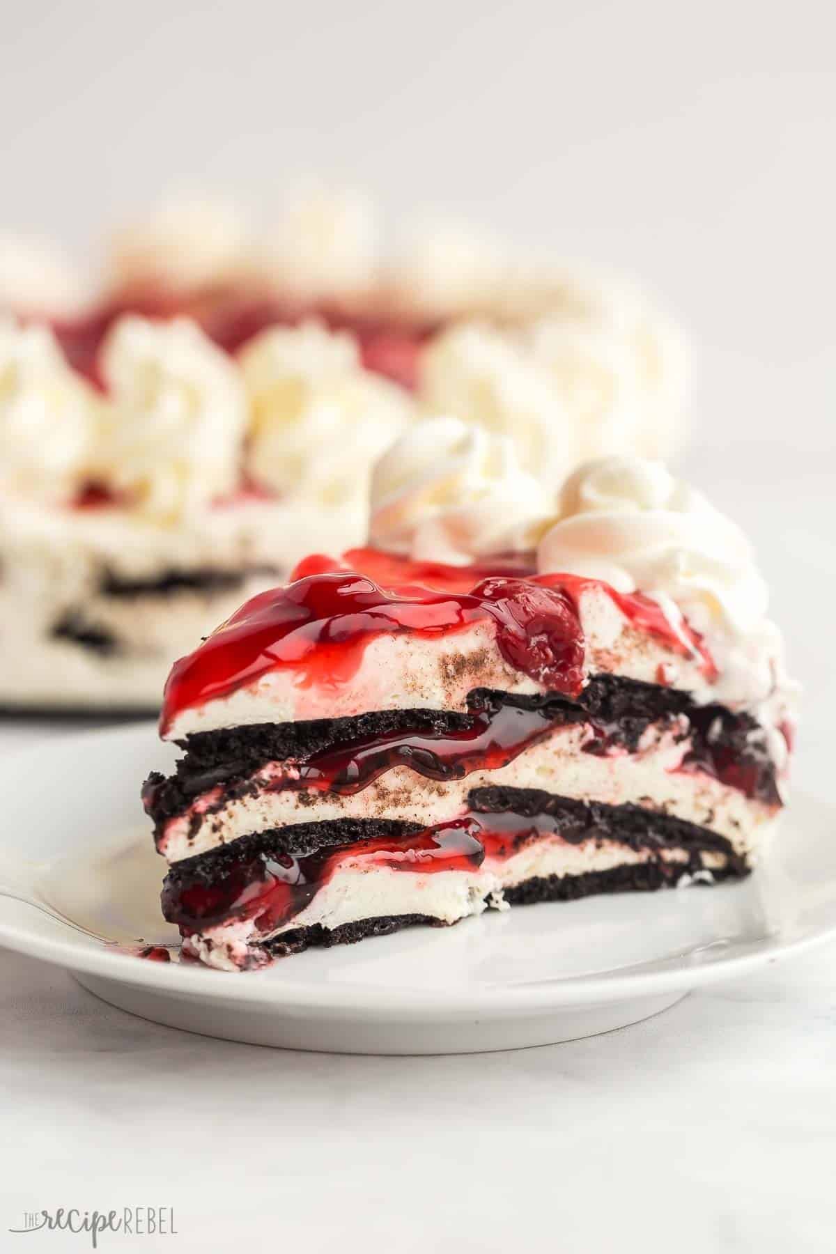 Ce gâteau glacé sans cuisson aux cerises noires est un dessert facile qui est parfait pour l'été ! Il ne nécessite que QUATRE ingrédients. Un morceau de gâteau glacé aux cerises noires sur une assiette blanche.