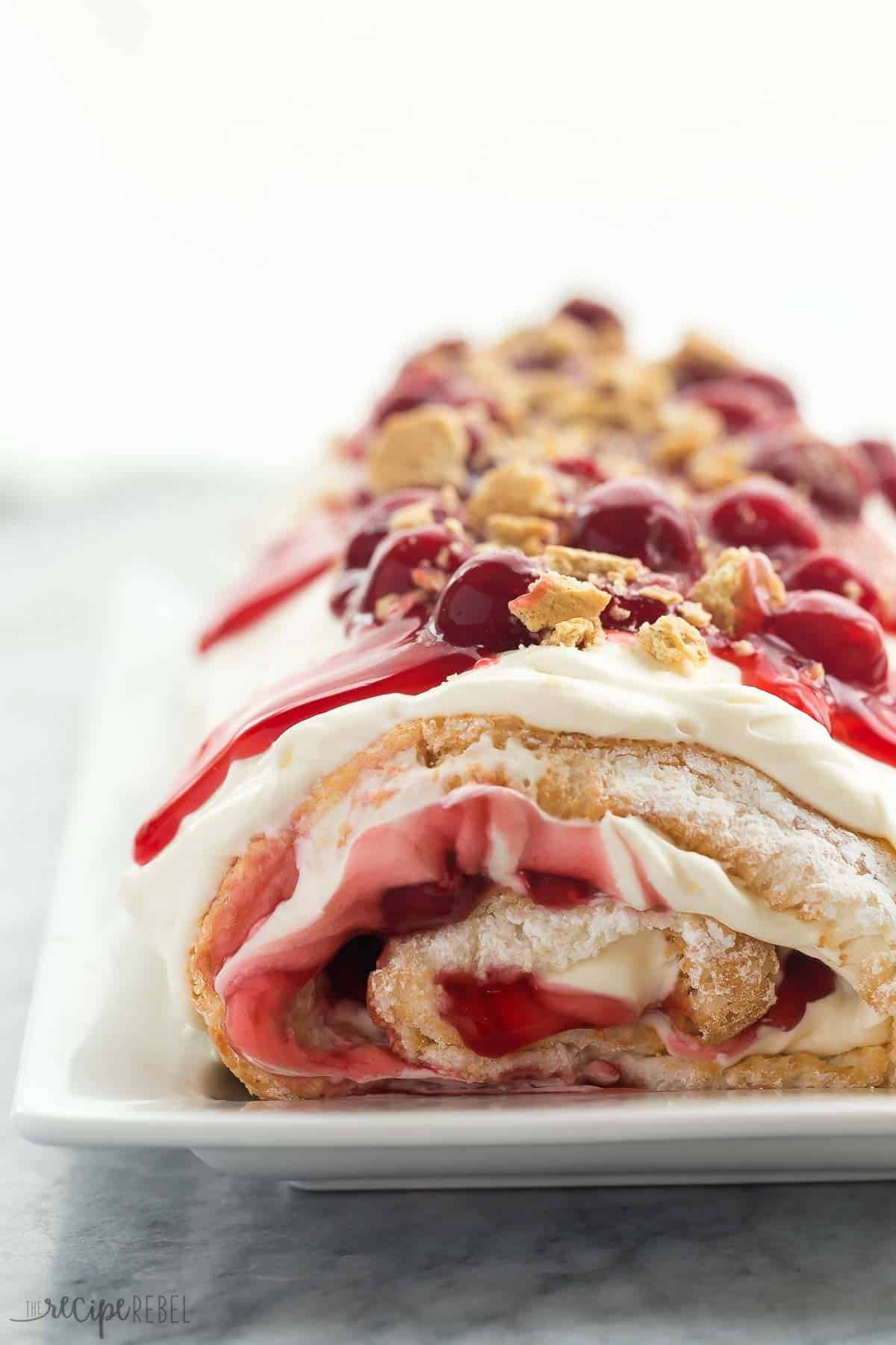 Roulé de gâteau angélique au fromage frais cerise sur un plat blanc.