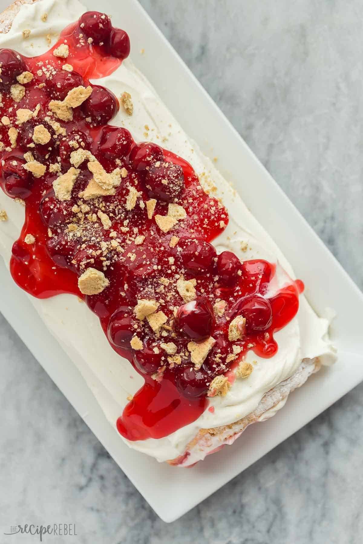 Image du dessus de tout le roulé de gâteau angélique au fromage frais cerise sur un plat blanc.