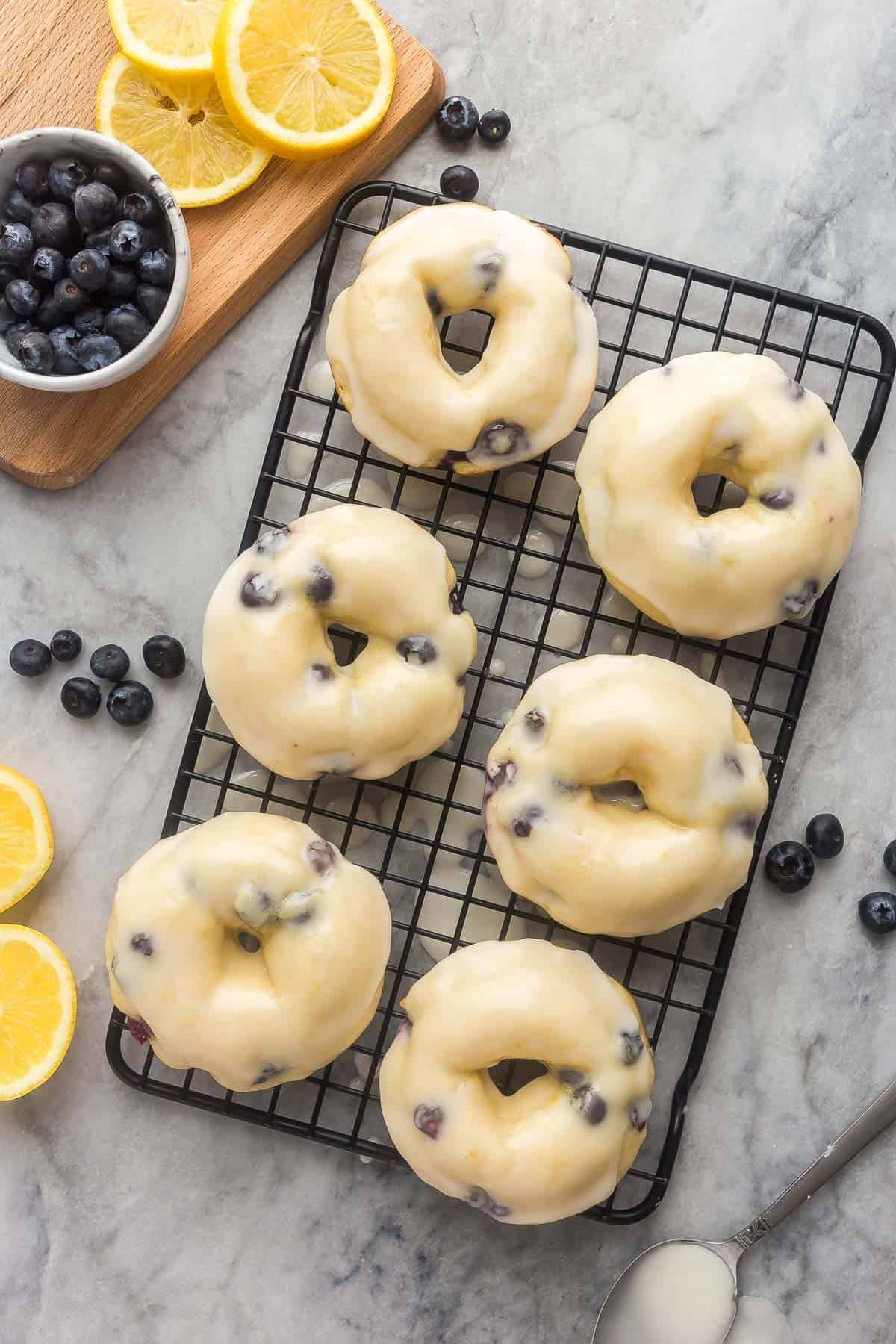 Image aérienne de beignets aux myrtilles cuits sur une grille noire avec glaçage.
