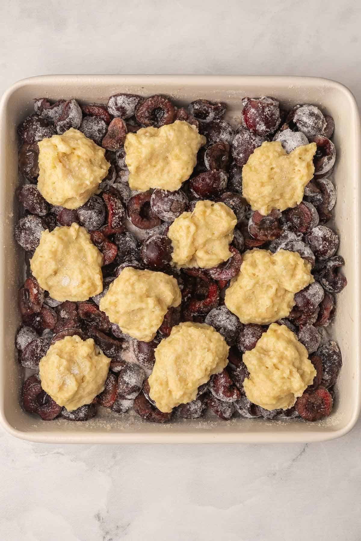 Plat carré de cobbler aux cerises prêt pour le four.