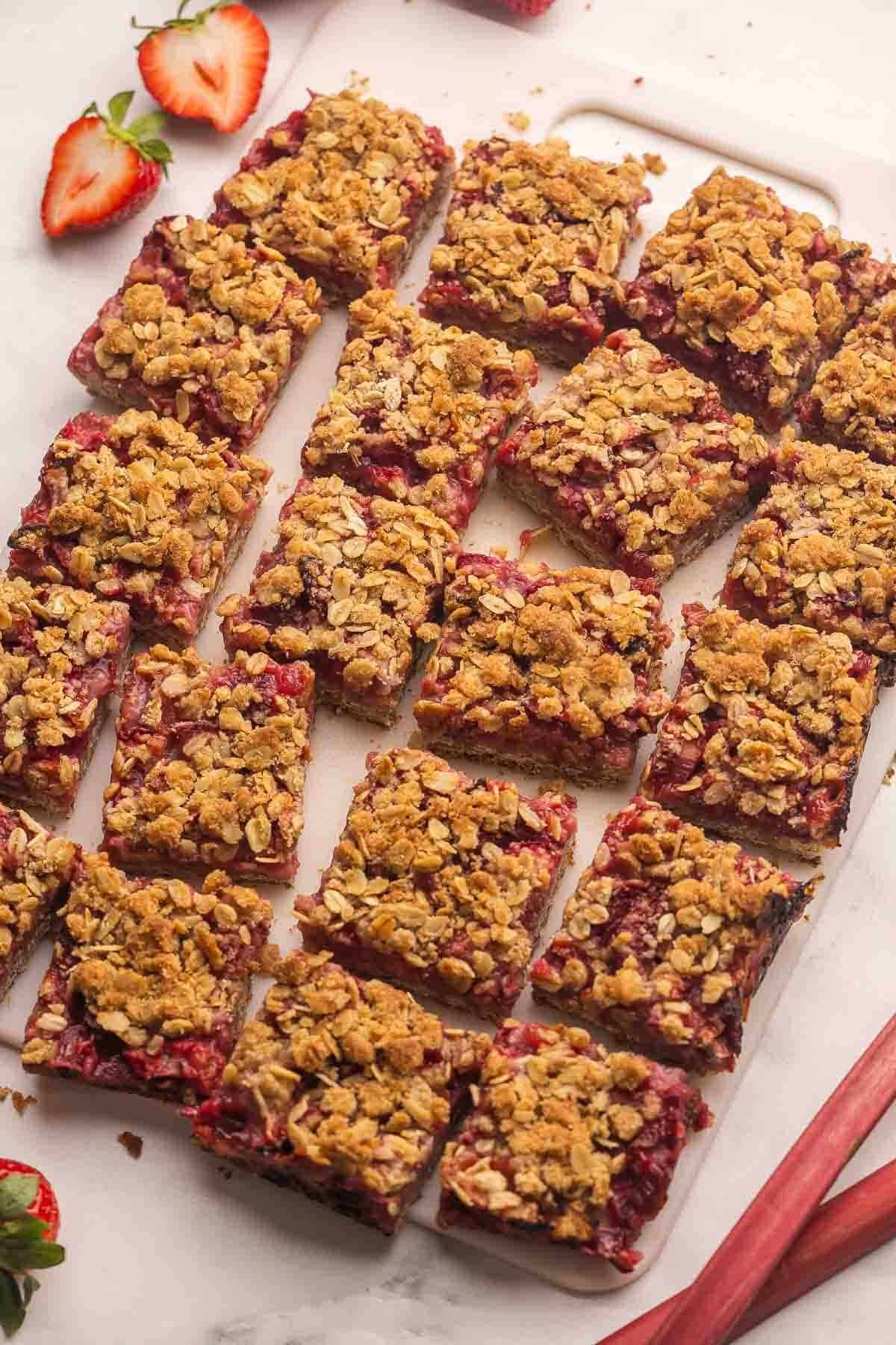 Barres aux fraises et rhubarbe coupées sur une planche à découper blanche.