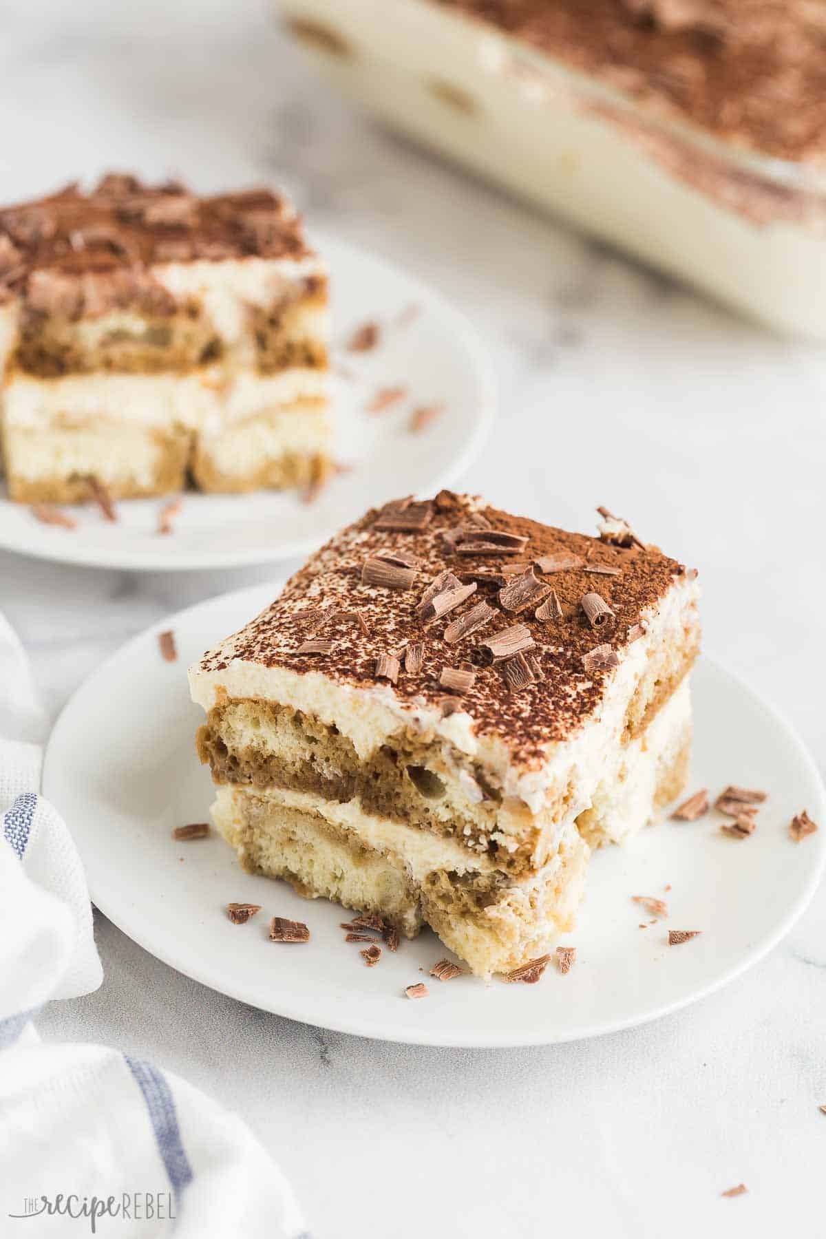 Deux pièces de tiramisu sur des assiettes à dessert avec le plat en arrière-plan.