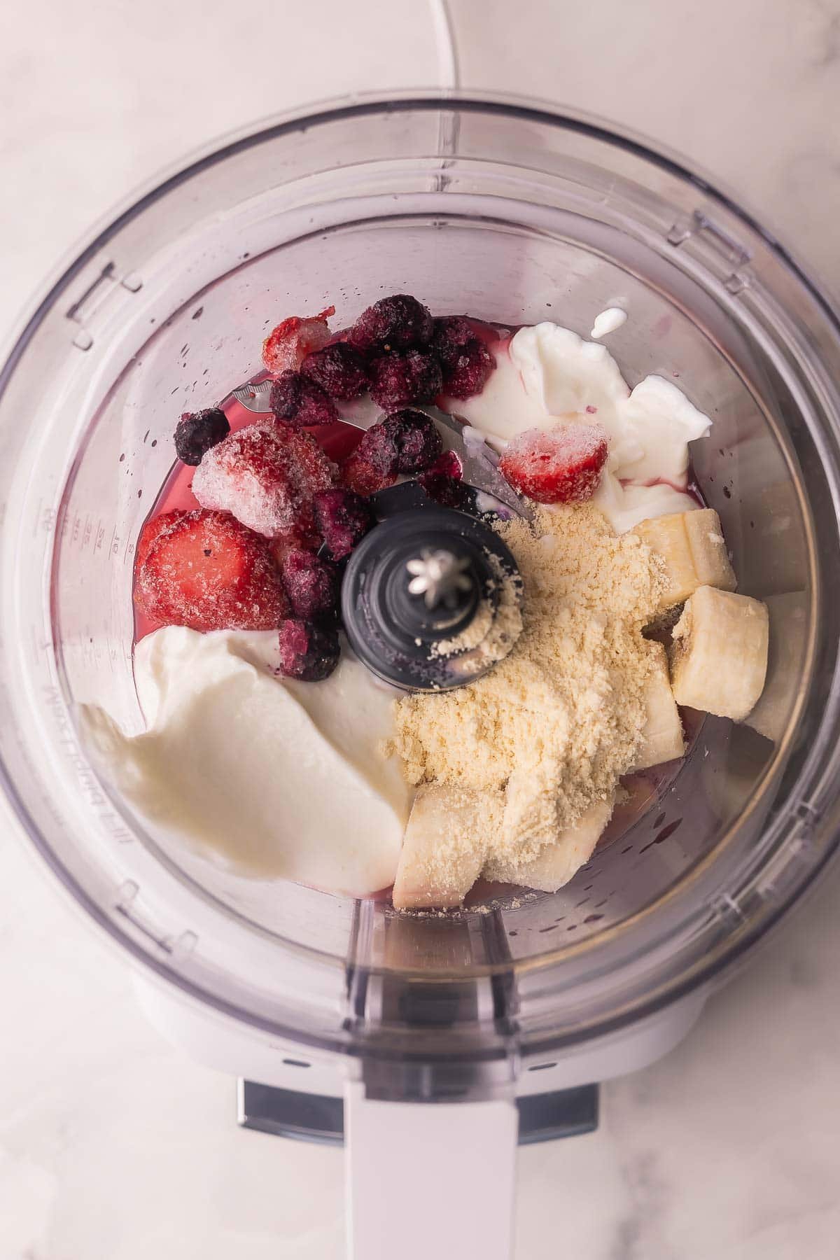un mélangeur plein d'ingrédients de smoothie non mélangés.