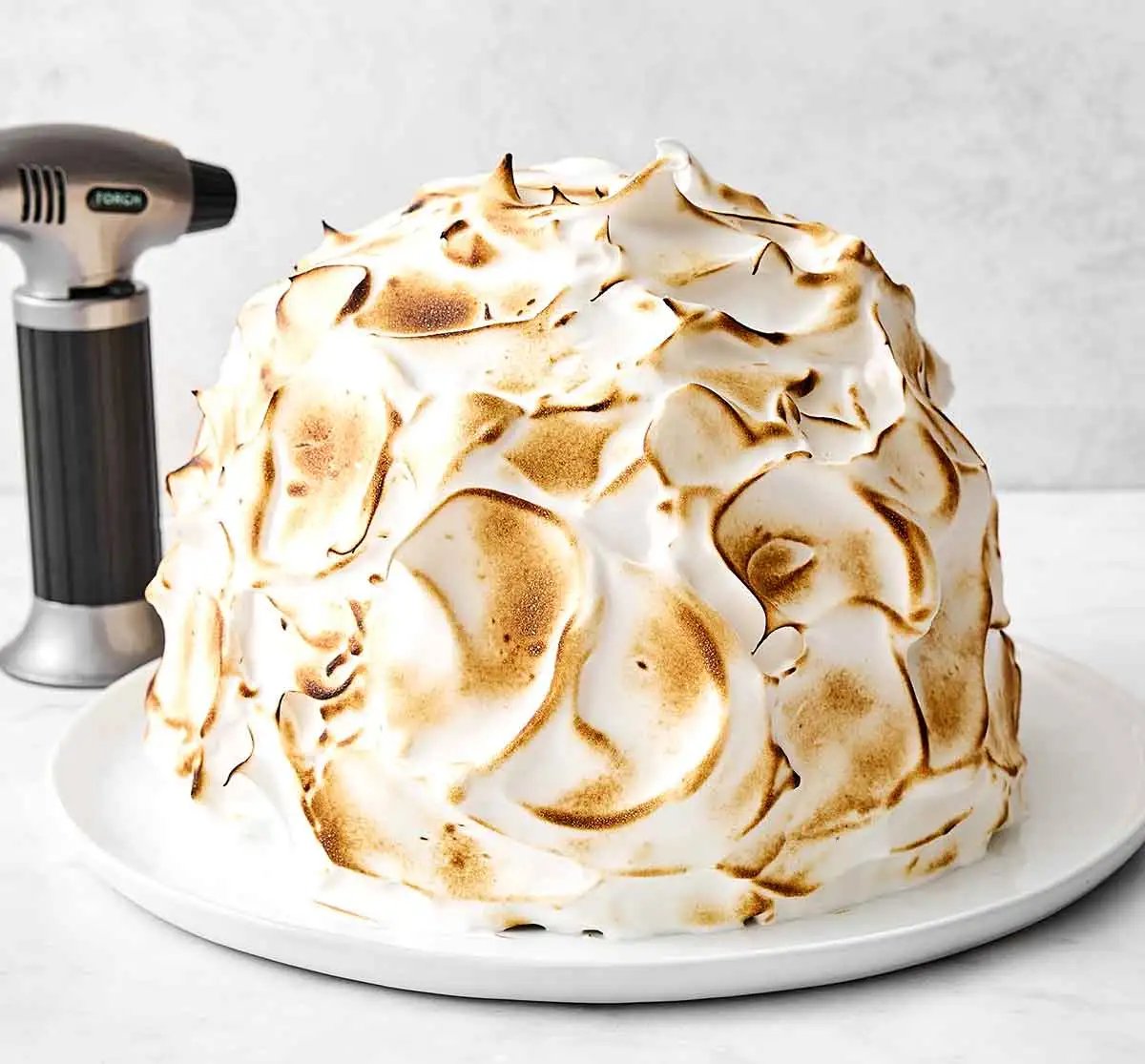 Flamber la meringue sur un Baked Alaska.