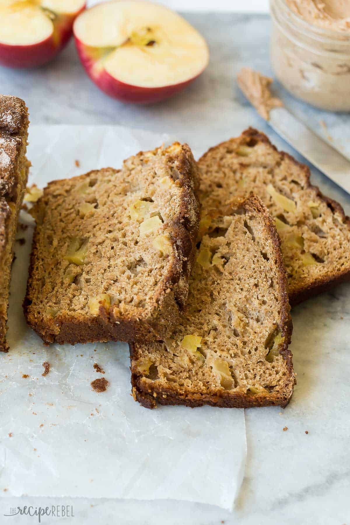 trois tranches de pain aux pommes à la cannelle coupées et disposées sur du papier parchemin.
