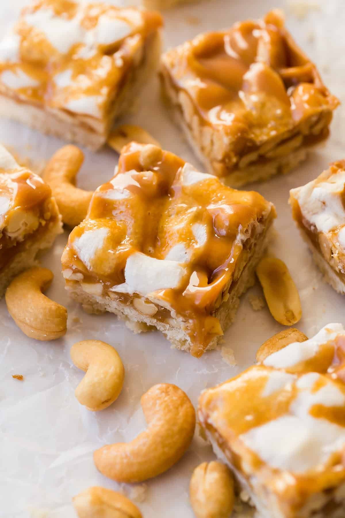 Barres de noix au caramel découpées en carrés sur du papier sulfurisé.