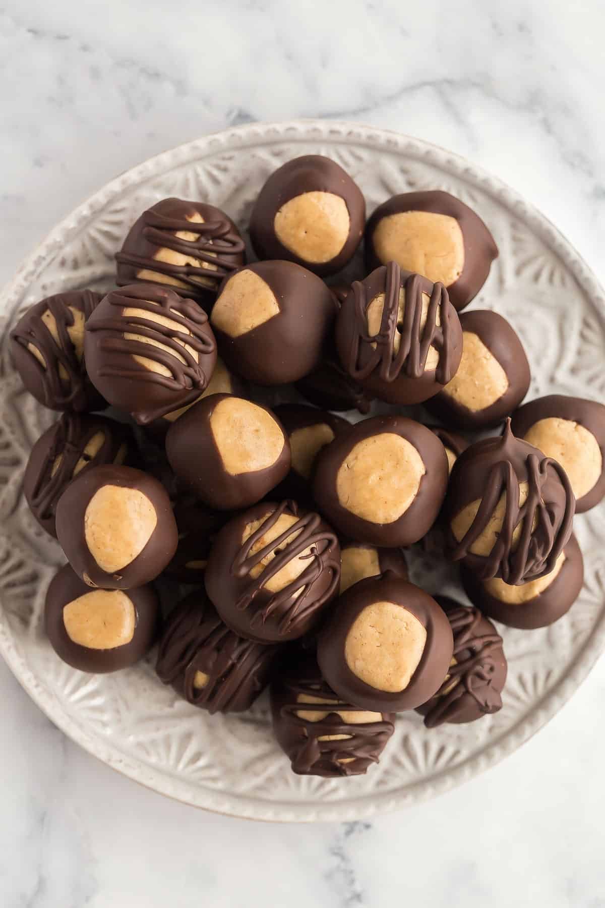 Un tas de billes de beurre de cacahuète trempées dans le chocolat sur une assiette.