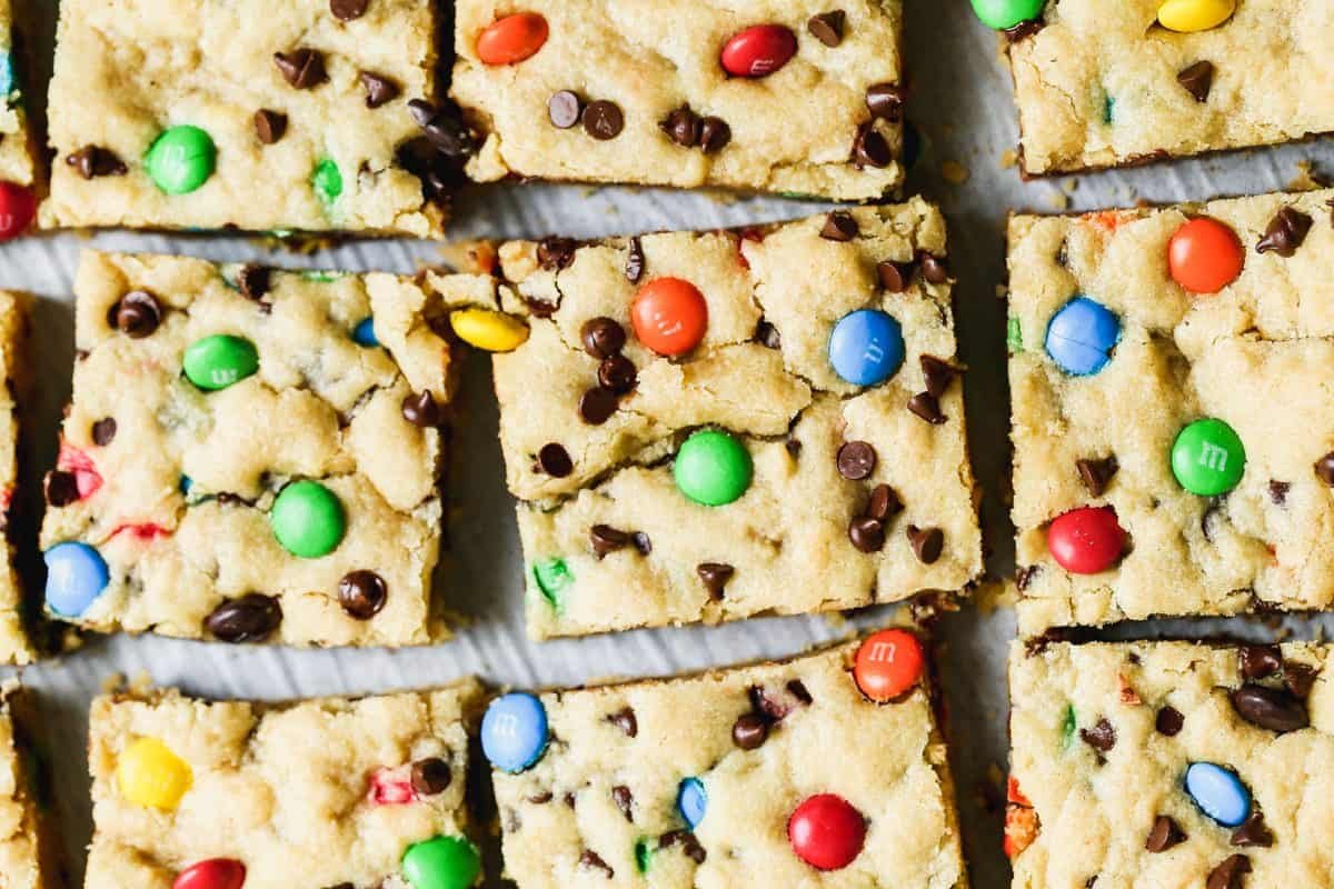 Les meilleures barres de cookies M&M sont moelleuses, chewy et chargées de ces bonbons colorés et mini pépites de chocolat. Arrêtez de prendre des boules de pâte à cookies et faites-les cuire dans un plat à la place !