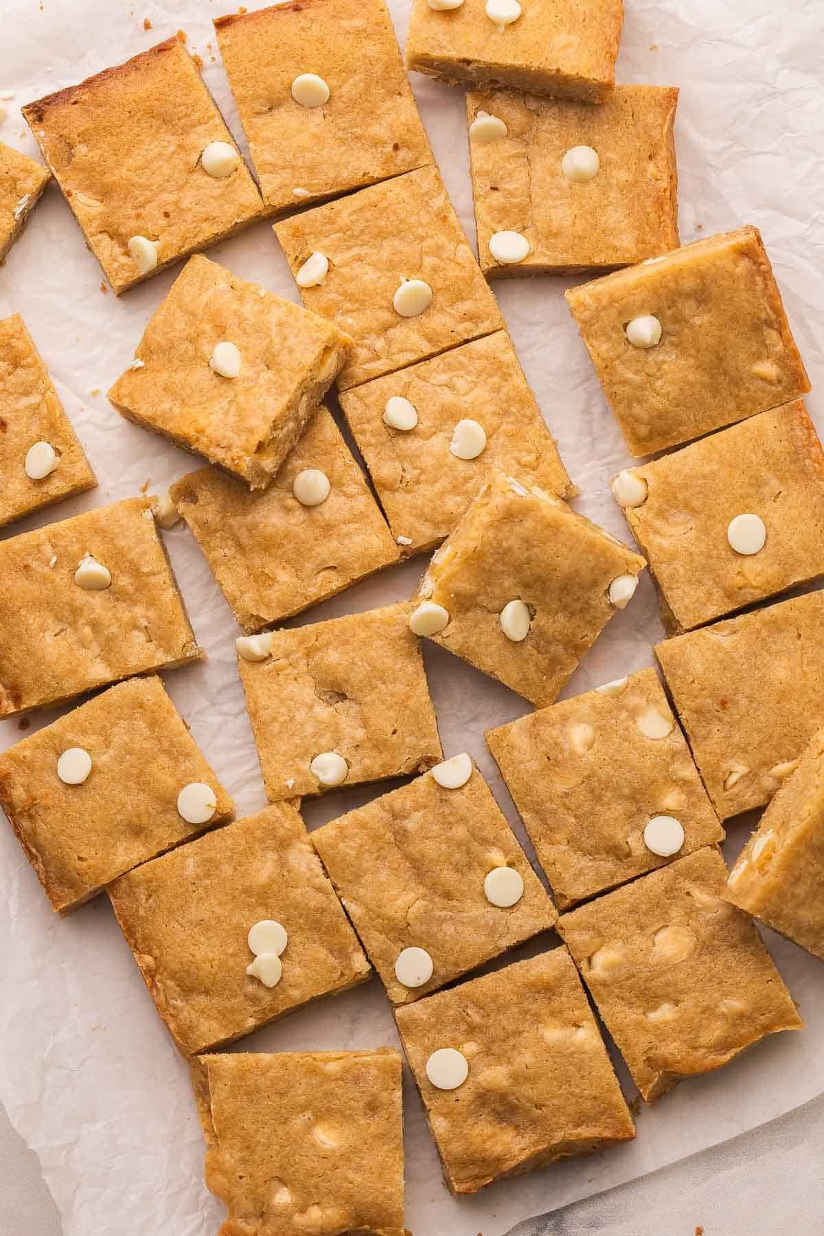 blondies fudgy coupés en carrés sur du papier sulfurisé.