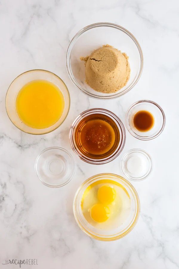 Ces Tartelettes au Beurre sont un classique canadien qui se prépare en seulement 25 minutes ! Des coques de pâtisserie maison sont remplies d'une garniture riche, au sucre brun (raisins en option !), puis cuites jusqu'à ce qu'elles soient beurrées et feuilletées à l'intérieur et gooey à l'intérieur. ingrédients de la garniture de tartelette au beurre sur fond blanc