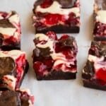 Gros plan de carrés de brownies au cheesecake aux cerises avec un dessus marbré.