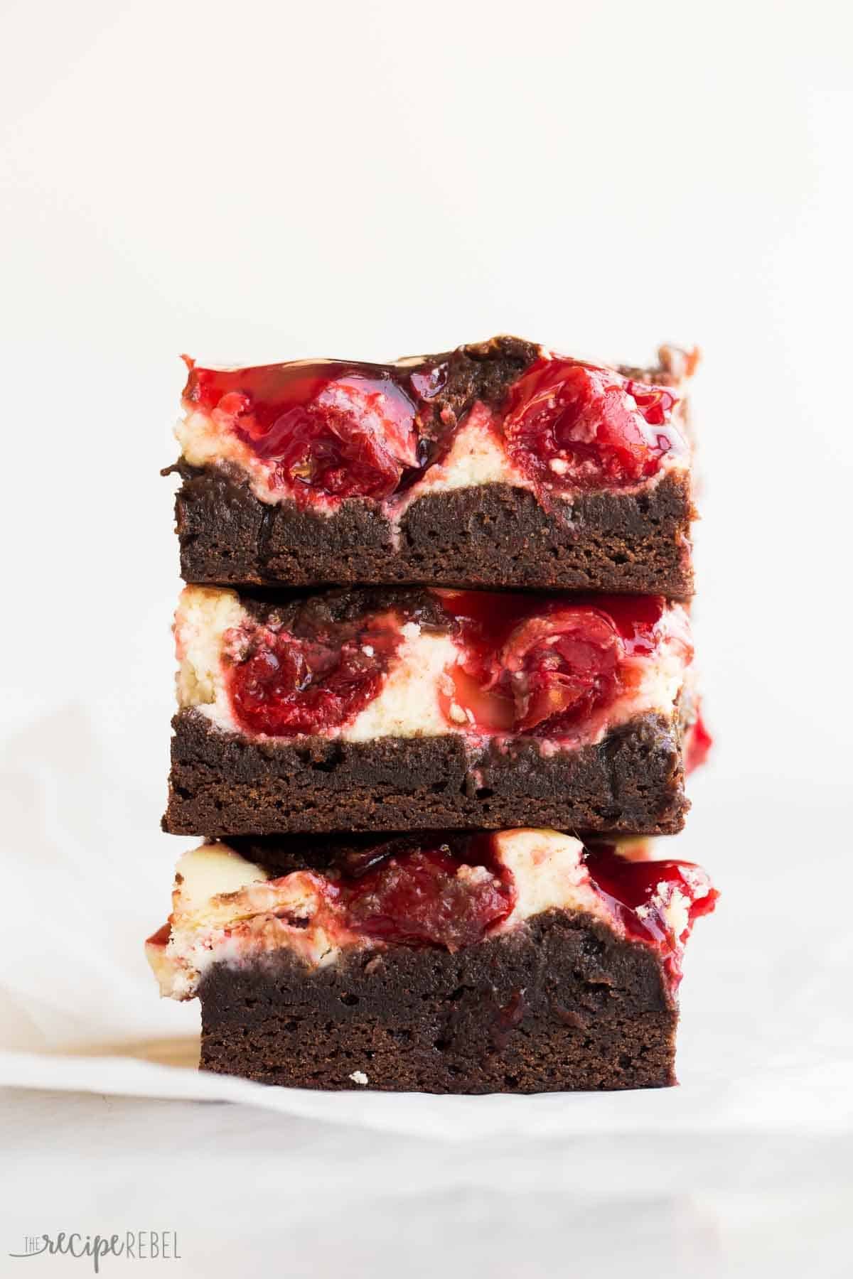 Empilement de trois brownies au cheesecake aux cerises avec un dessus de cerise.