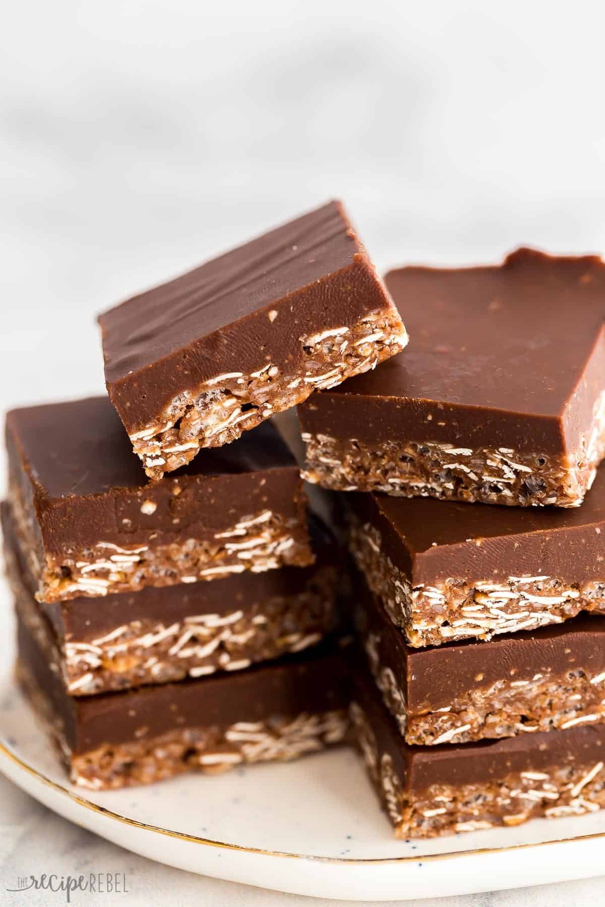 Barres de chocolat croquantes empilées avec une couche de flocons d'avoine sur une assiette blanche.