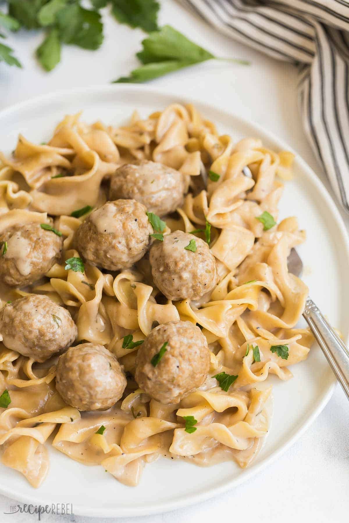 Boulettes de viande suédoises et nouilles à la cuve instantanée cuisent des boulettes de viande congelées et des nouilles aux œufs dans une sauce crémeuse au bœuf. Juste 5 minutes de préparation et une seule casserole ! Cette recette est un favori familial pour la saison des plats réconfortants. Assiette de boulettes de viande suédoises et de nouilles à côté d'une serviette en lin rayé.