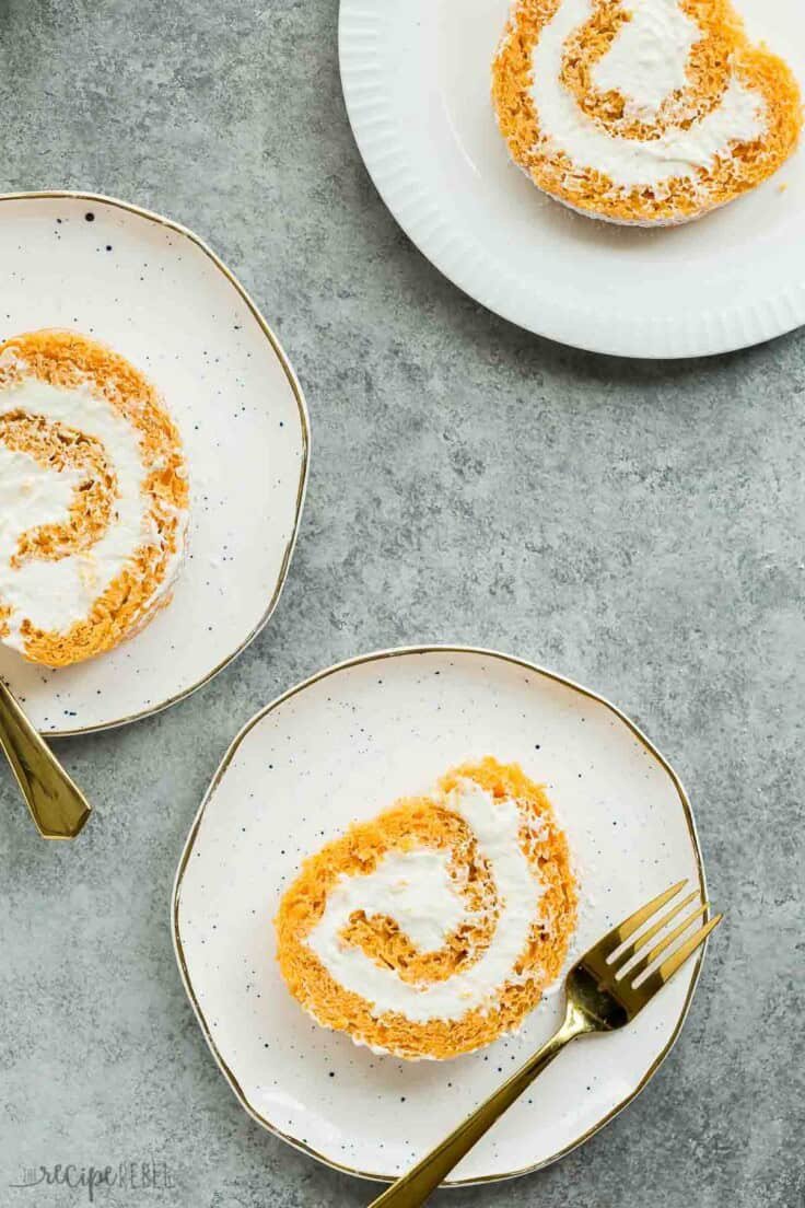 Tranches de gâteau roulé à la citrouille avec garniture crémeuse sur des assiettes à bord doré.