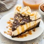 Gros plan de part de cheesecake aux tortues montrant les couches crémeuses, le caramel et les noix de pécan.